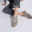 Person wearing beige sneakers on a light gray background